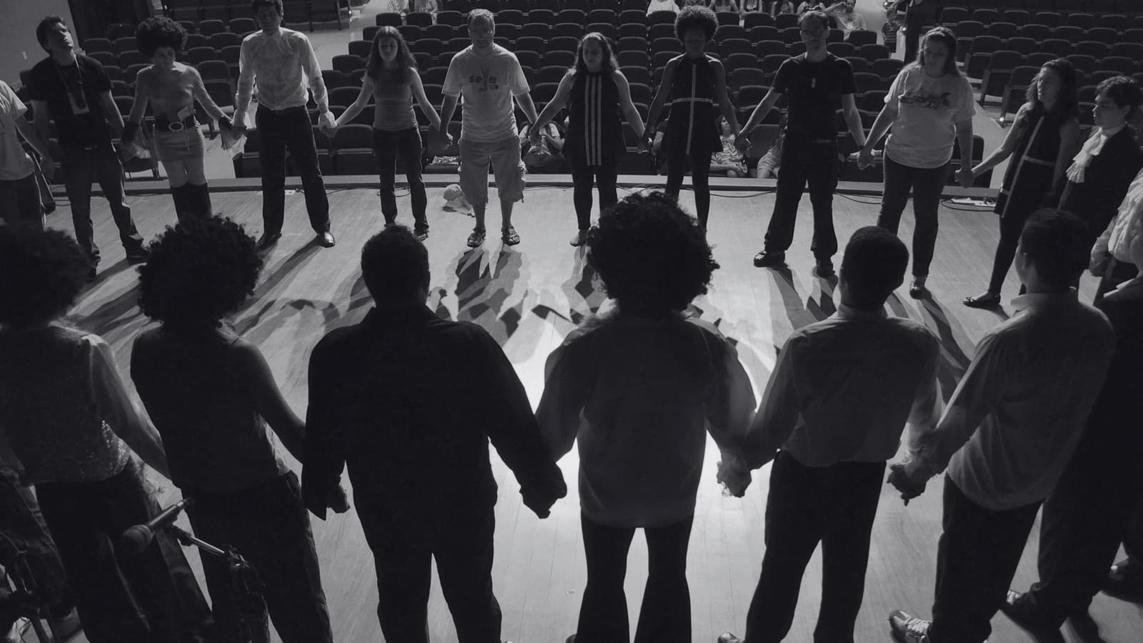 Theatre ensemble standing in a circle holding hands